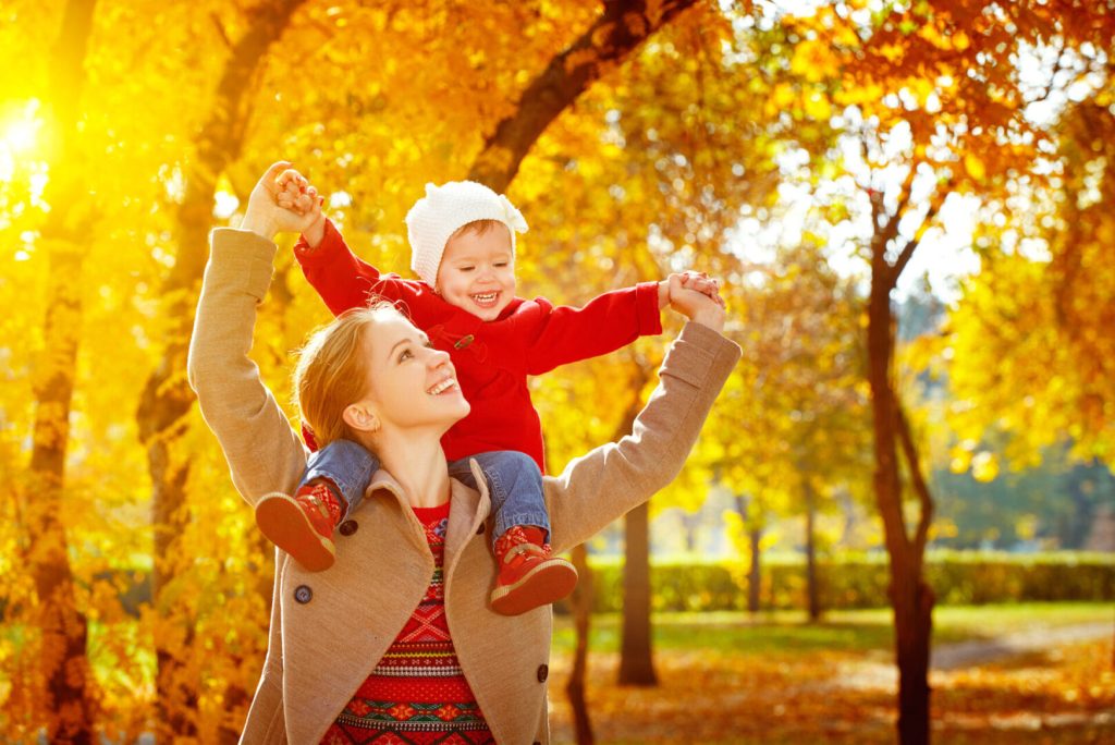 Mother and daughter frolicking in a park on a sunny, autumn day.