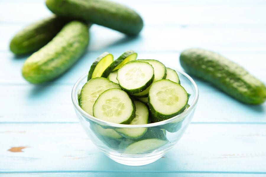 A bowl of cucumbers on top of a table.
